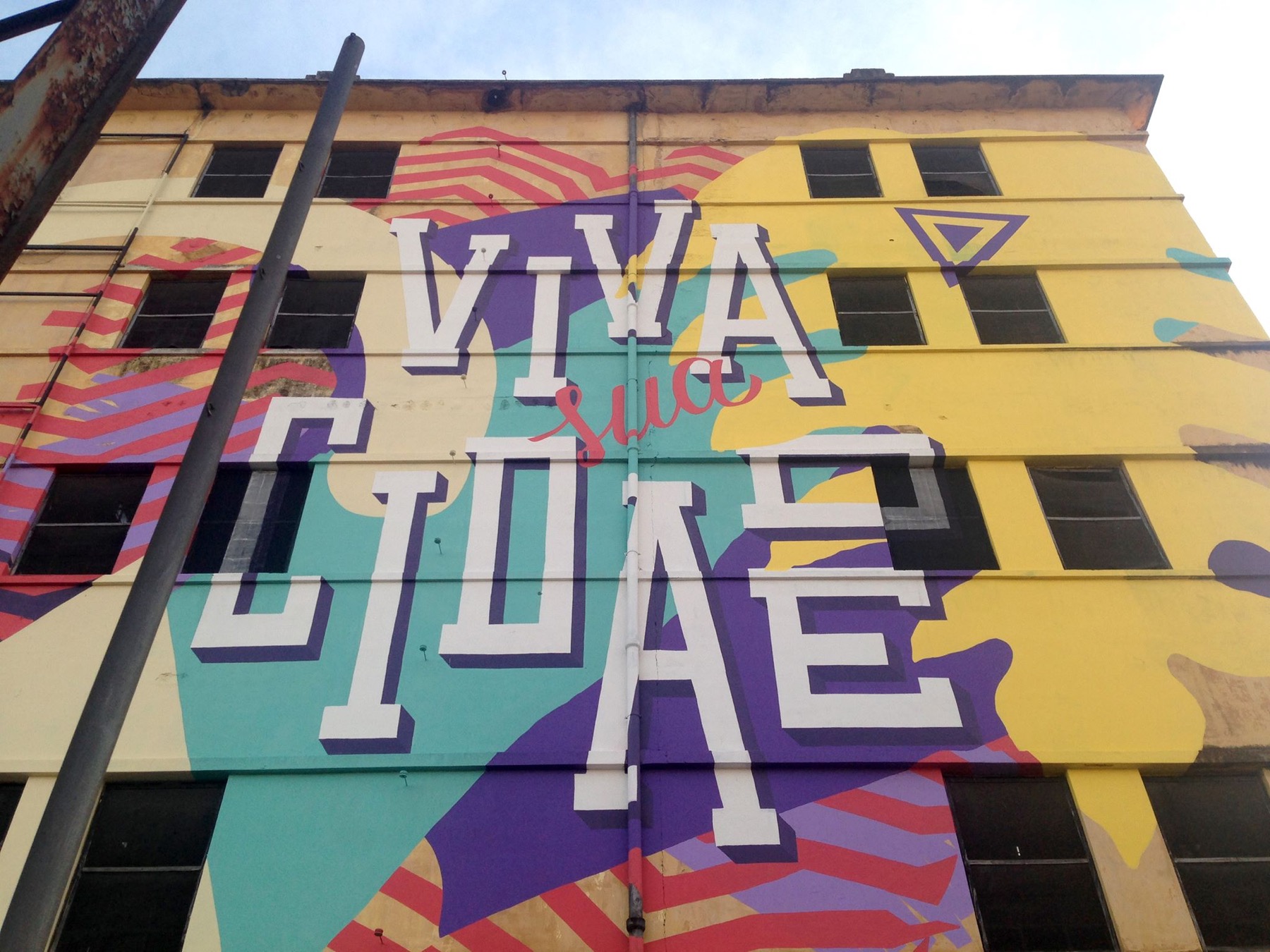 Mural Viva Sua Cidade: tipografia grande e colorida pintada na fachada de um prédio no Rebouças